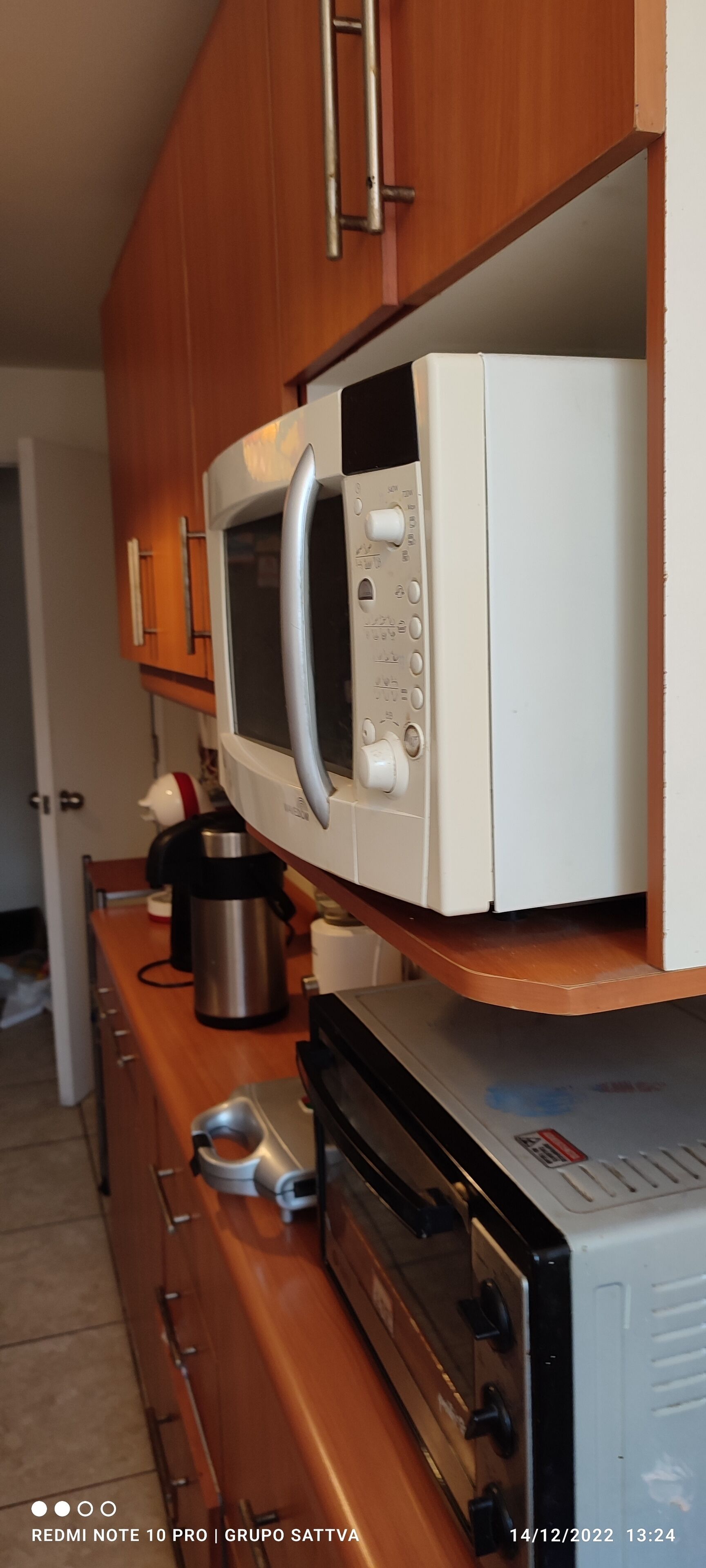 Een keuken met een magnetron, een koffiezetapparaat en een broodrooster op een houten aanrecht.
