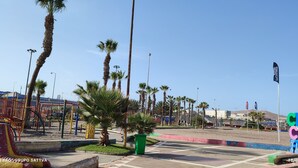 A playground with climbing structures and palm trees.