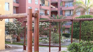 A playground with a metal swing set and a palm tree in the background.