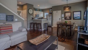 A modern living room with a sofa, coffee table, and a dining area with chairs and a table. - Spacious 4BR TownHome in Kissimmee, perfect for family getaways! (Kissimmee)