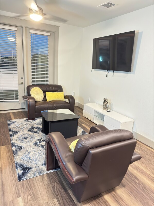 A living room with a brown leather sofa, a black coffee table, and a white side table.