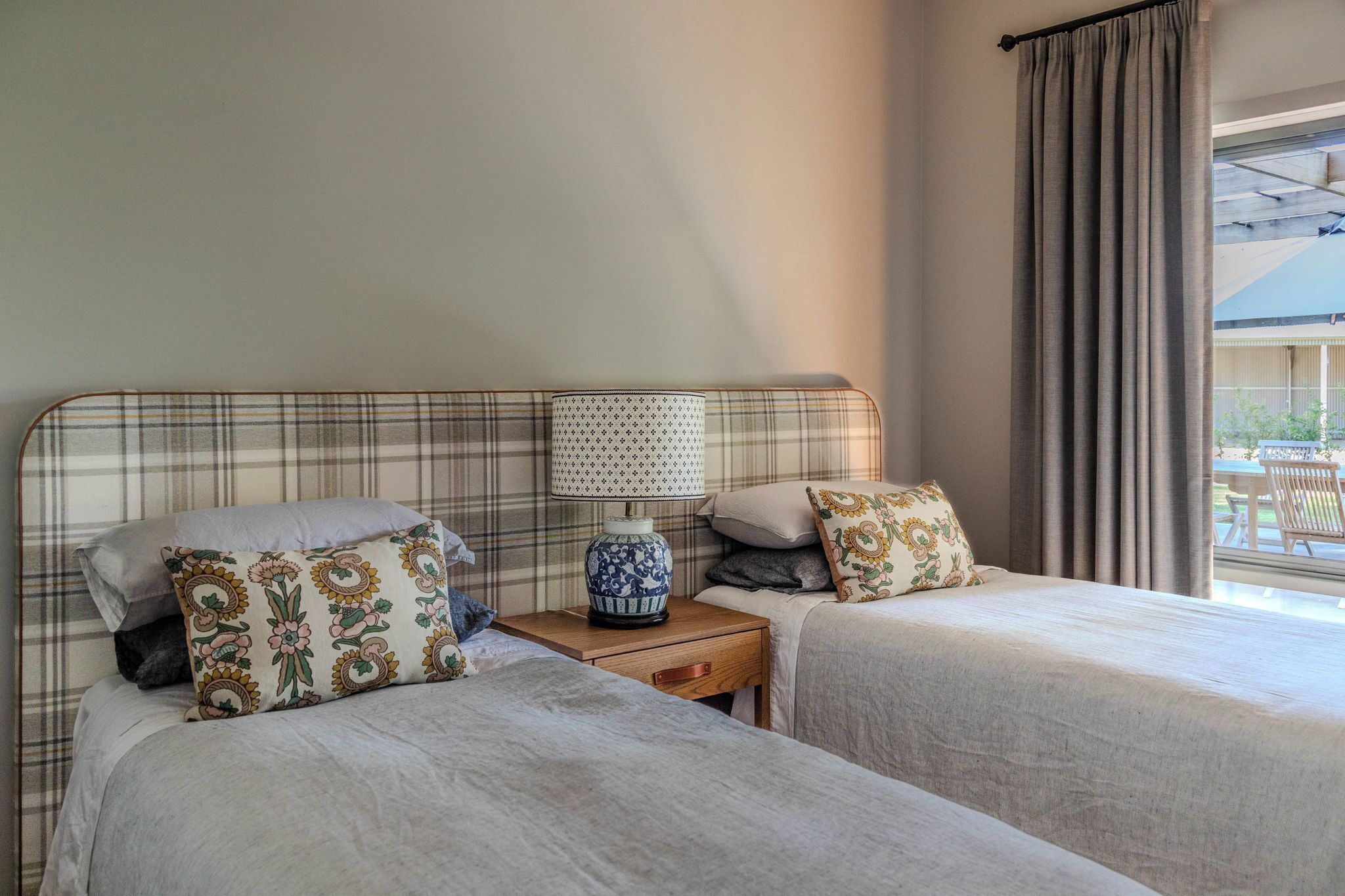Een hotelkamer met twee bedden, een nachtkastje met een lamp en uitzicht op het omliggende landschap.