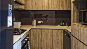 A modern kitchen with wooden cabinets, a built-in oven, a microwave, and a sink.