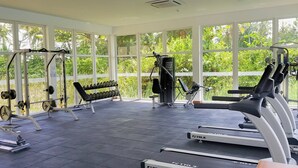A gym with cardio machines, weightlifting equipment, and dumbbells.