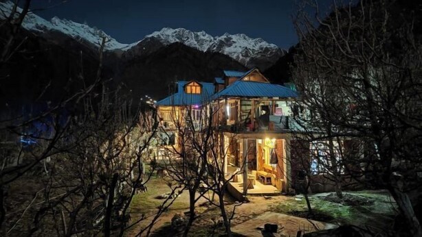A two-story lodge with a balcony, surrounded by snow-capped mountains. - Yalakhom (Sosan)