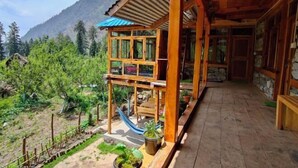 A wooden cabin with a balcony, a hammock, and a view of the surrounding forest and mountains. - Yalakhom (Sosan)