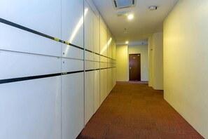 A hallway with lockers, carpeted floor, and a door at the end. - MY Fame Hotel (Rasah)