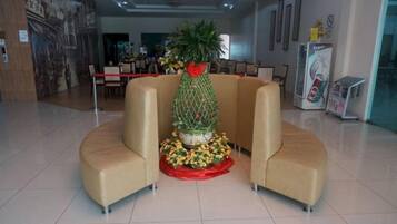 A lobby with a reception desk, a large potted plant, and a seating area with a curved sofa.