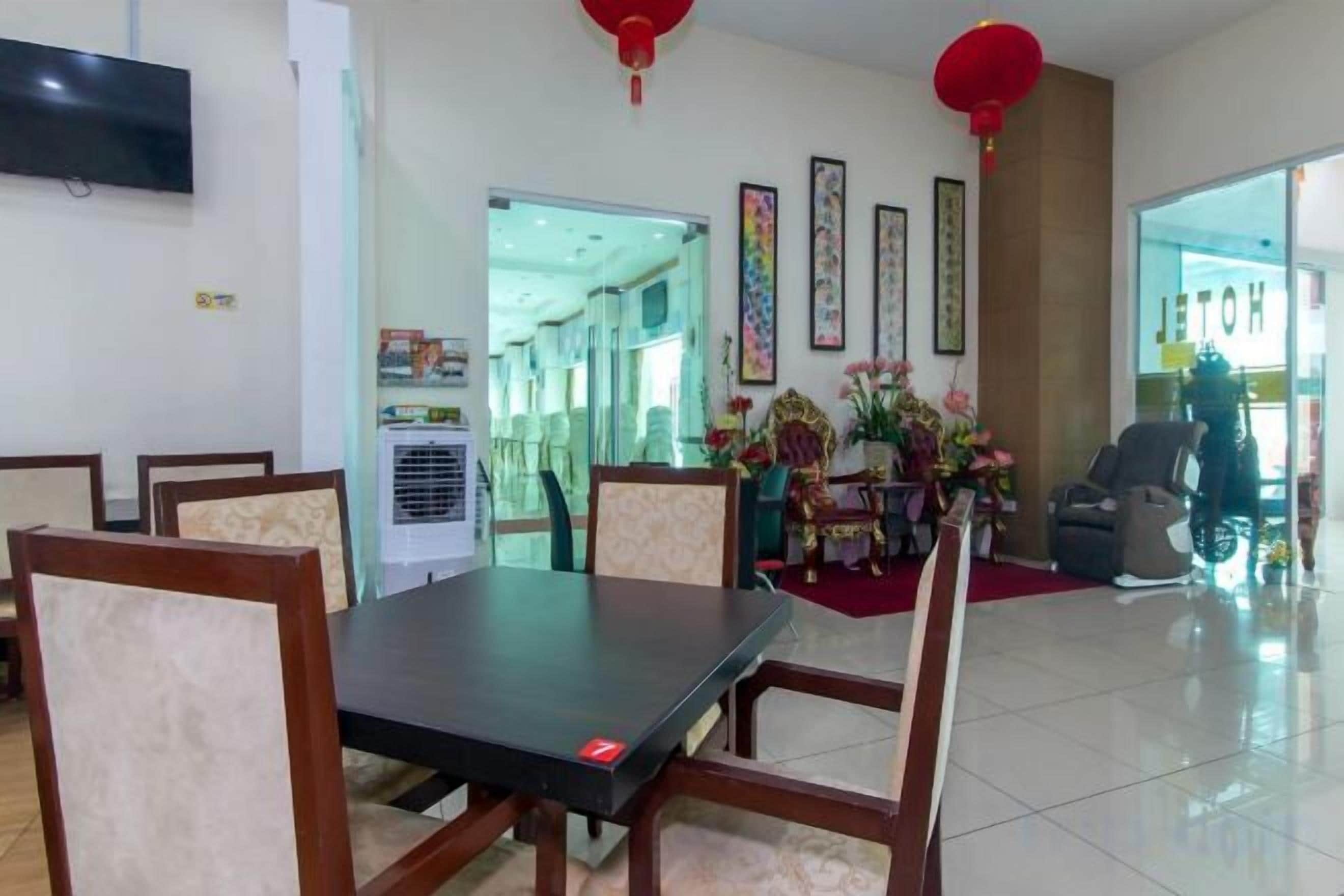 A hotel dining area with a table and chairs, a television on the wall, and a red lantern.