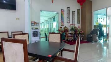 A hotel dining area with a table and chairs, a television on the wall, and a red lantern.