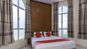 A bedroom with a large bed, curtains, and a view through a window. - MY Fame Hotel (Rasah)