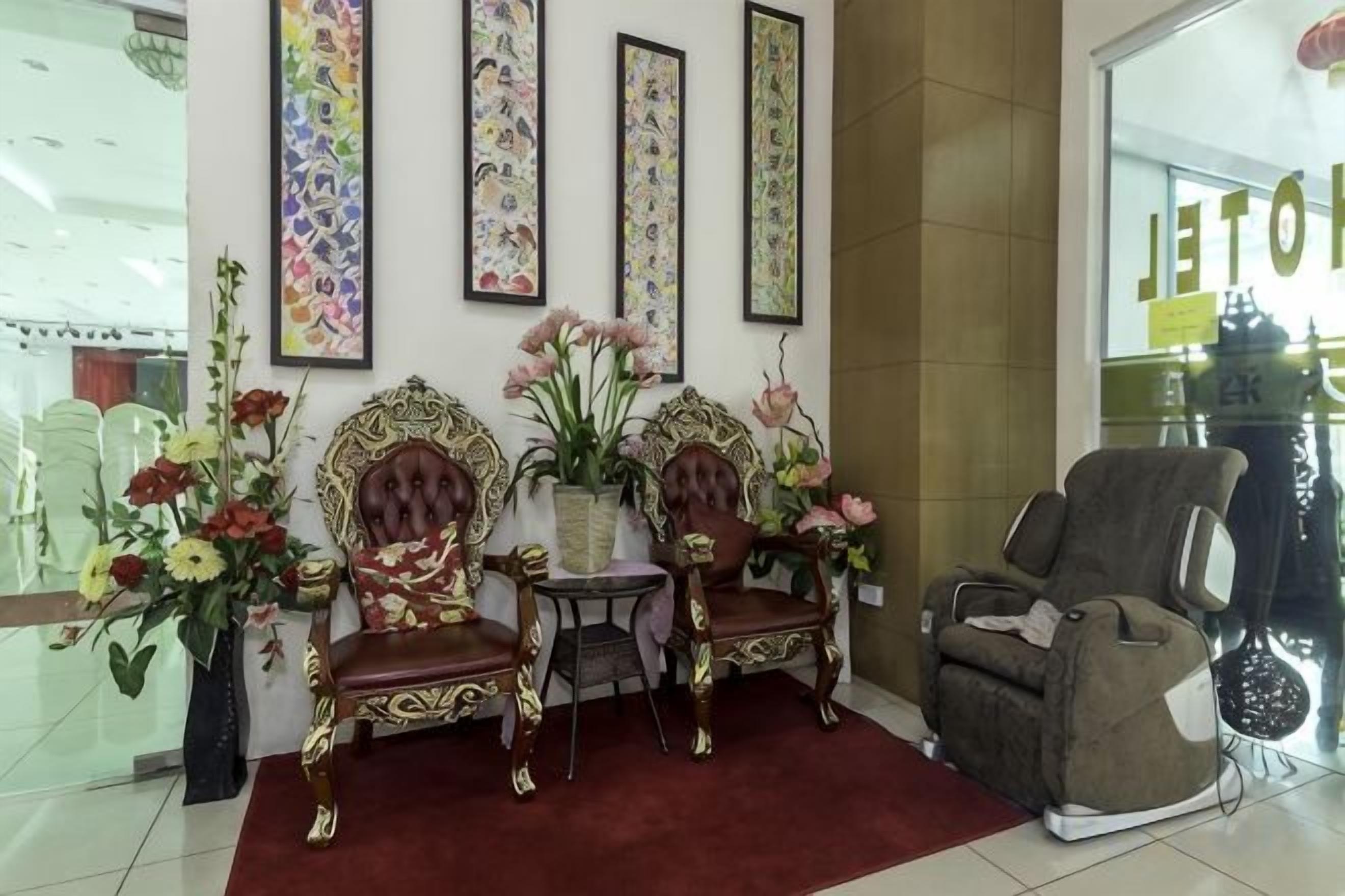 A room with two ornate chairs, a massage chair, and a vase with flowers.