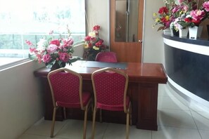 A dining area with a wooden table, two red chairs, and a vase of flowers. - MY Fame Hotel (Rasah)
