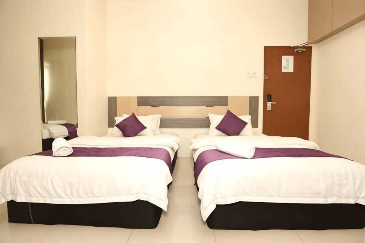 A hotel room with two beds, a wooden headboard, a mirror, and a door.