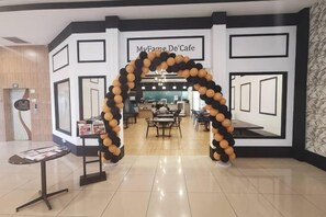 A cafe with a black and white geometric wall design, a black and white balloon arch, and a counter with a menu. - MY Fame Hotel (Rasah)
