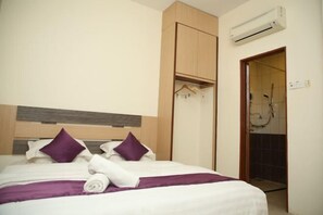 A hotel room with a bed, a wooden wardrobe, an air conditioning unit, and a shower area. - MY Fame Hotel (Rasah)