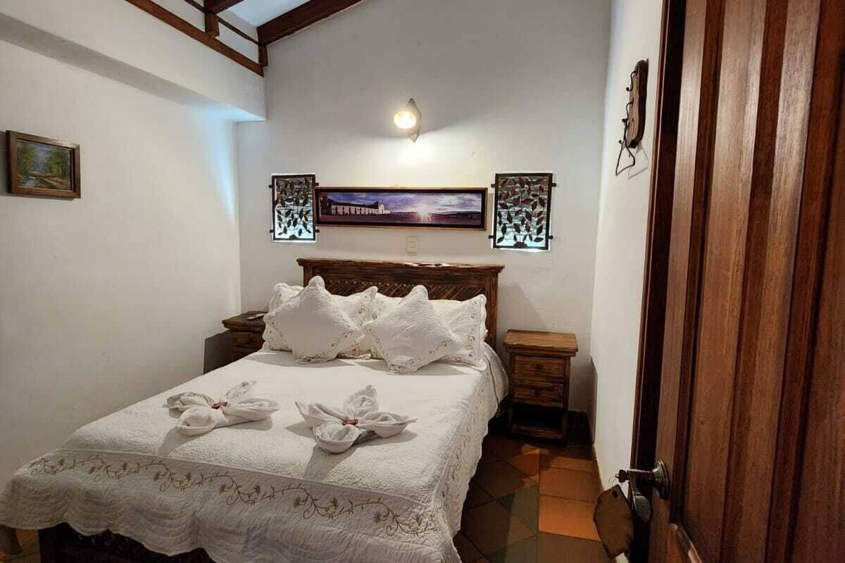 Ein Schlafzimmer mit einem Bett, einem Holz-Kopfteil, zwei Nachttischen, einer Tür und einer an der Wand befestigten Leuchte.