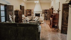A spacious living room with a fireplace, wooden furniture, and a high ceiling with exposed beams. - Amazing Historic  Spanish House with AC, WIFI Cable and an amazing Courtyard.  (Antigua Guatemala)