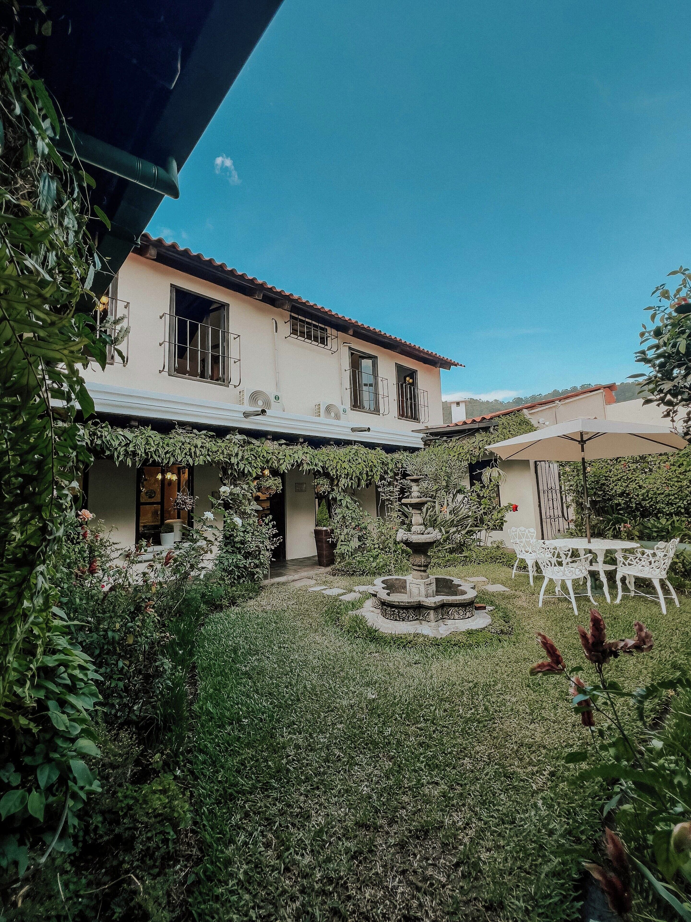 A two-story building with a garden patio, a fountain, and outdoor seating.