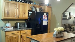 Una cocina con armarios de madera, un refrigerador negro, una isla de madera y un tostador.