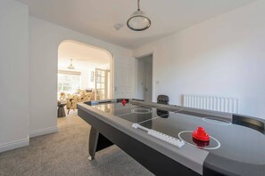 A modern room with a foosball table, a dining area with a table and chairs, and a large window.