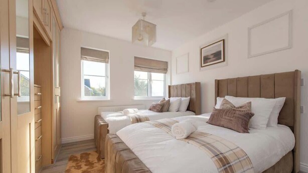 A bedroom with two beds, a wooden wardrobe, and a large window. - Modern 5BR * Game Room * Free Parking * Sleeps 10 (Hornchurch)