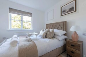 A bedroom with a bed, bedside table, lamp, and window.