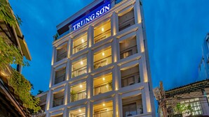 A multi-story building with balconies, a sign reading "TRUNG SON BUILDING," and a sign indicating "TRUNG SON" hotel. - DHTS Business Hotel & Apartment (Ho Chi Minh City)