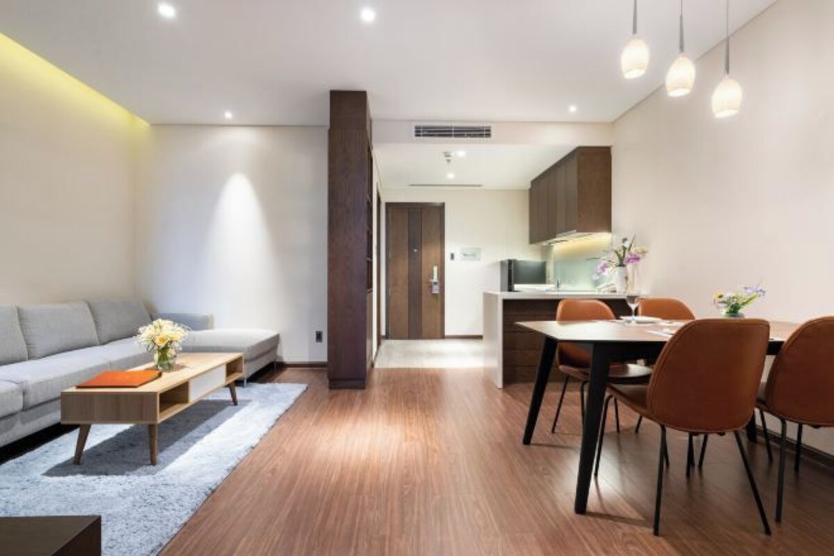 A modern living room with a sofa, coffee table, and dining area with chairs.