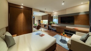 A modern hotel room with a bed, a desk, a TV, and a seating area. - DHTS Business Hotel & Apartment (Ho Chi Minh City)