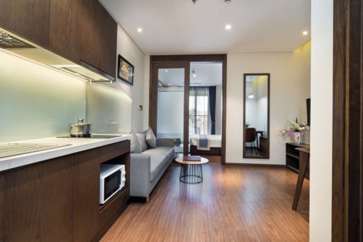 A modern kitchen with a built-in oven, a grey sofa, and a small round table.