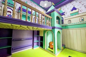 A children's playroom with a bunk bed, a playhouse, and a green floor. - D'Primahotel Bandung (Sukajadi)