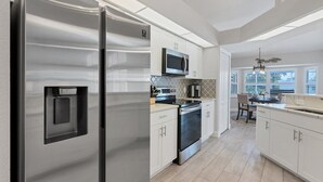 Une cuisine moderne dotée d’appareils électroménagers en acier inoxydable, de meubles blancs et d’un îlot central avec des sièges.