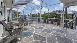 Eine Terrasse im Freien mit Steinplatten, Liegestühlen und Blick auf ein Gewässer.