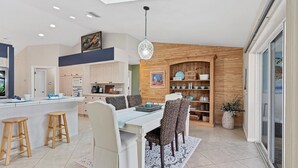 Een moderne keuken met een centraal eiland, houten kastjes en een eethoek met patroonstoelen.
