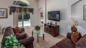 Ein Wohnzimmer mit Deckenventilator, Fernseher und Glastisch.