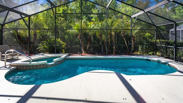 Ein überdachter Pool mit Glasverkleidung, umgeben von üppiger Vegetation.