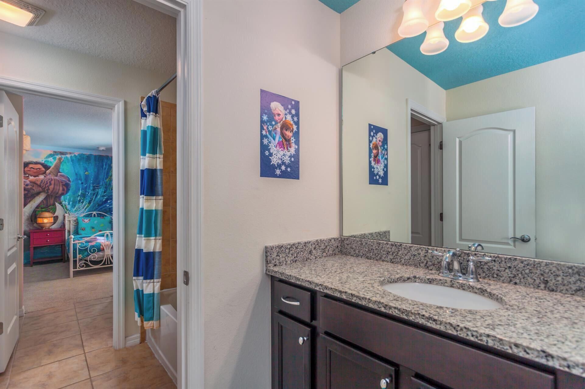 A bathroom with a granite countertop, a sink, a mirror, and two framed pictures on the wall.