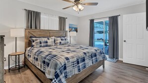 Een slaapkamer met een houten bed, een plafondventilator en uitzicht op het buiten.