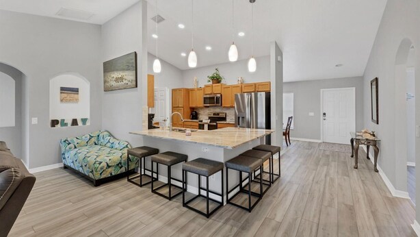 A spacious kitchen with a central island, wooden cabinets, and modern appliances.