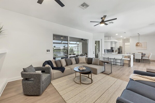A modern living room with a sectional sofa, a small round table, and a grey armchair.