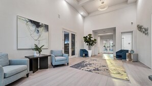 A spacious living room with a large abstract painting, two sofas, a coffee table, and a potted plant.
