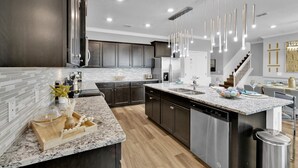 Una cocina moderna con armarios oscuros, encimera de granito y lavavajillas de acero inoxidable.
