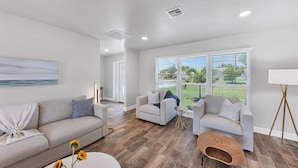 A spacious living room with a large window, a sofa, a chair, and a coffee table.