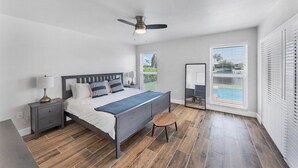 A bedroom with a bed, bedside tables, a ceiling fan, and a window with blinds.