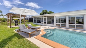 A modern outdoor pool area with lounge chairs and a pergola.