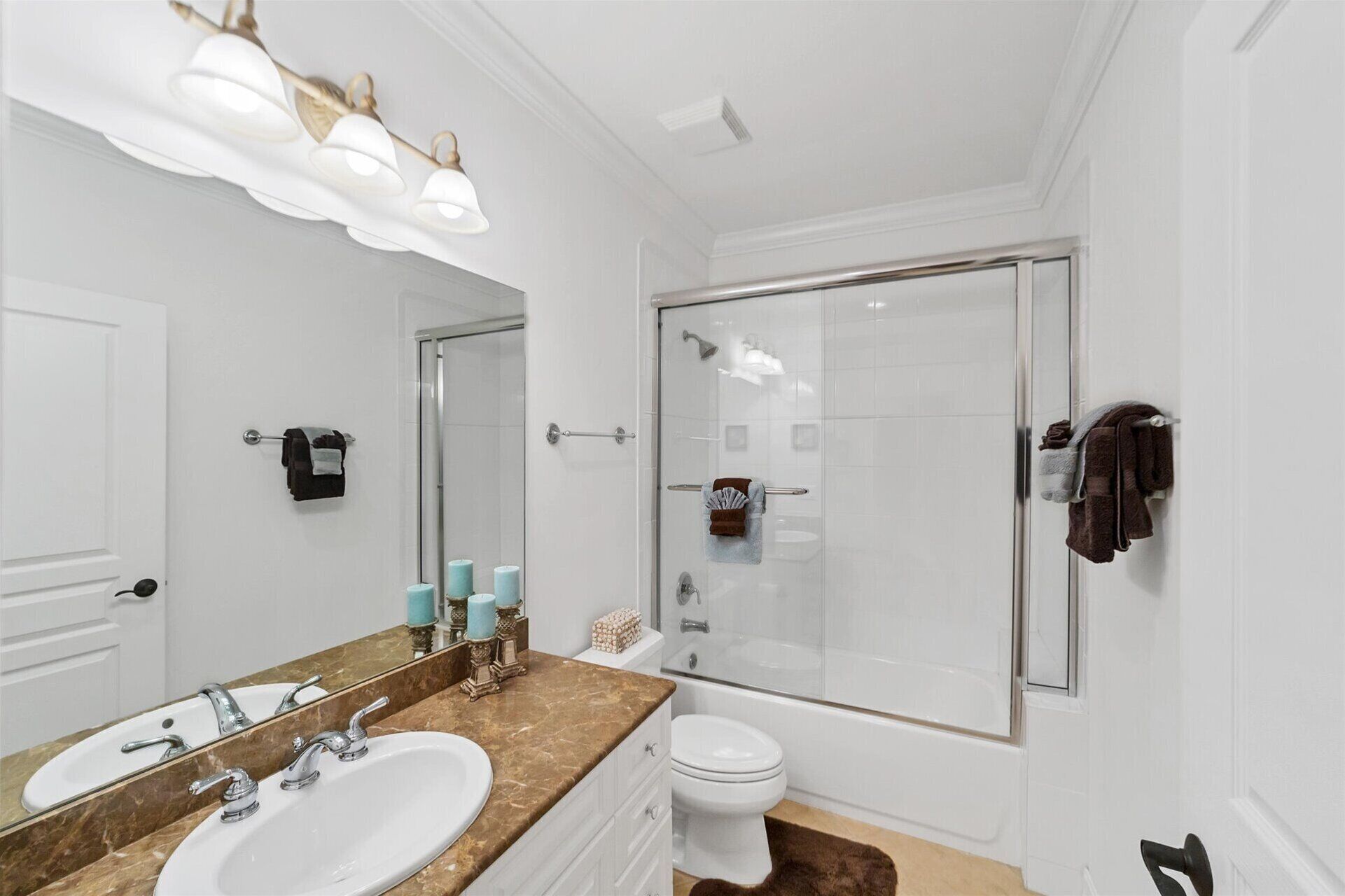 Une salle de bain moderne avec un grand miroir, un lavabo, des toilettes et une douche à parois de verre.