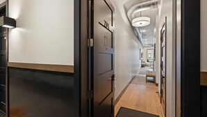 A modern hotel hallway with a wooden floor, a metal door with the number 204, and a ceiling with a light fixture. - Sunrise Escape at Downtown Whitefish (Whitefish)