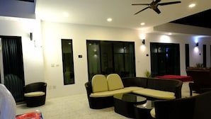 A modern living room with a sectional sofa, a coffee table, and a ceiling fan. - Natree Pool Villa Pattaya (Pattaya)