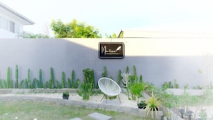 A garden area with a white chair, various plants, and a sign on the wall. - Natree Pool Villa Pattaya (Pattaya)